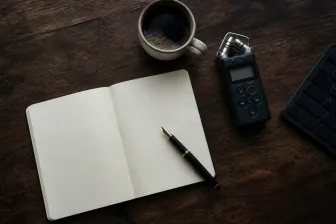 Houten schrijftafel met notitieboek en opnameapparatuur